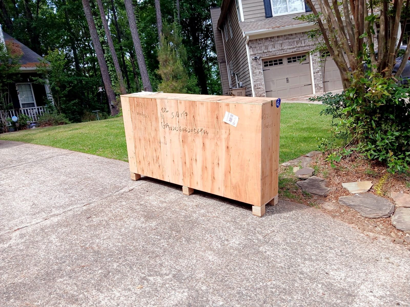 A large plywood freight crate at the bottom of a residential driveway.