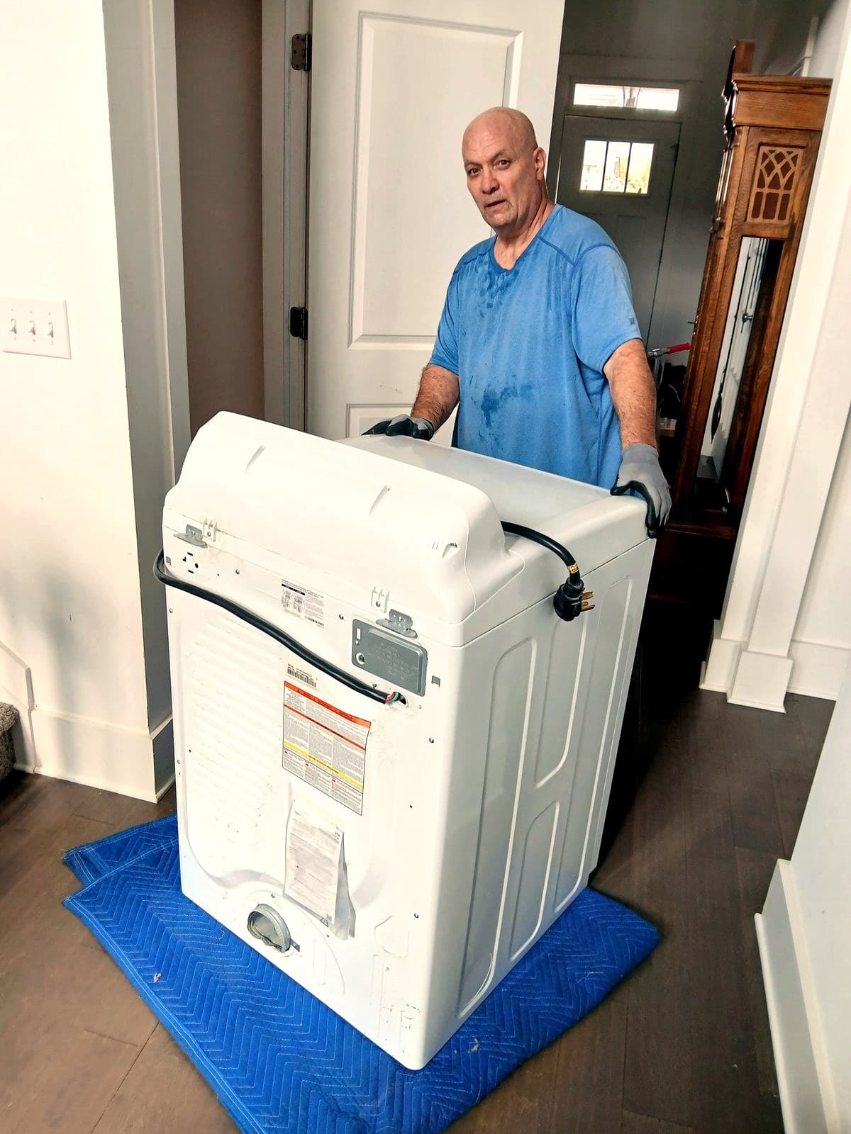 Gary guiding a dryer on a blanket through an interior doorway.