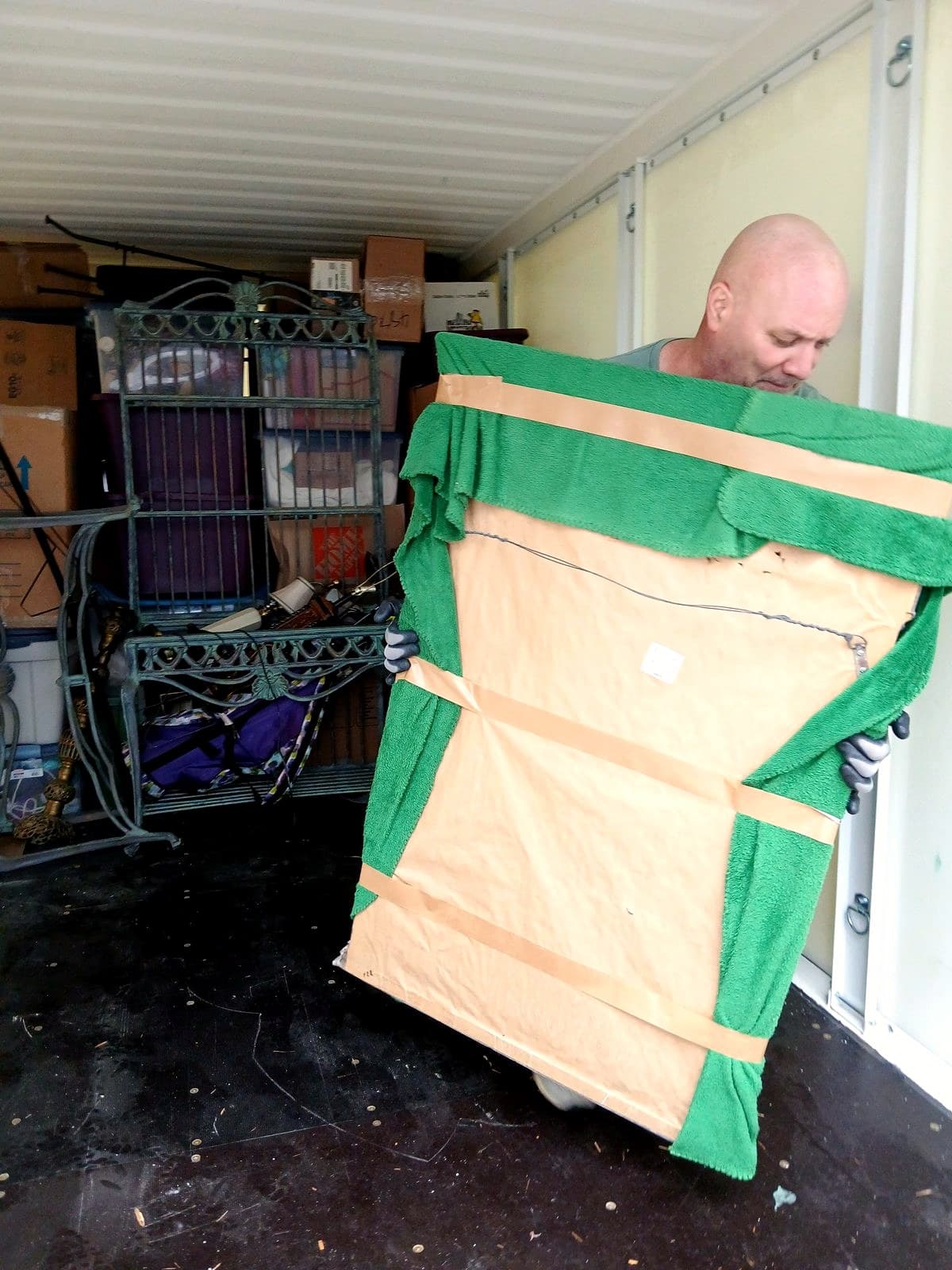 Gary moving furniture wrapped in green moving blankets inside a POD container.